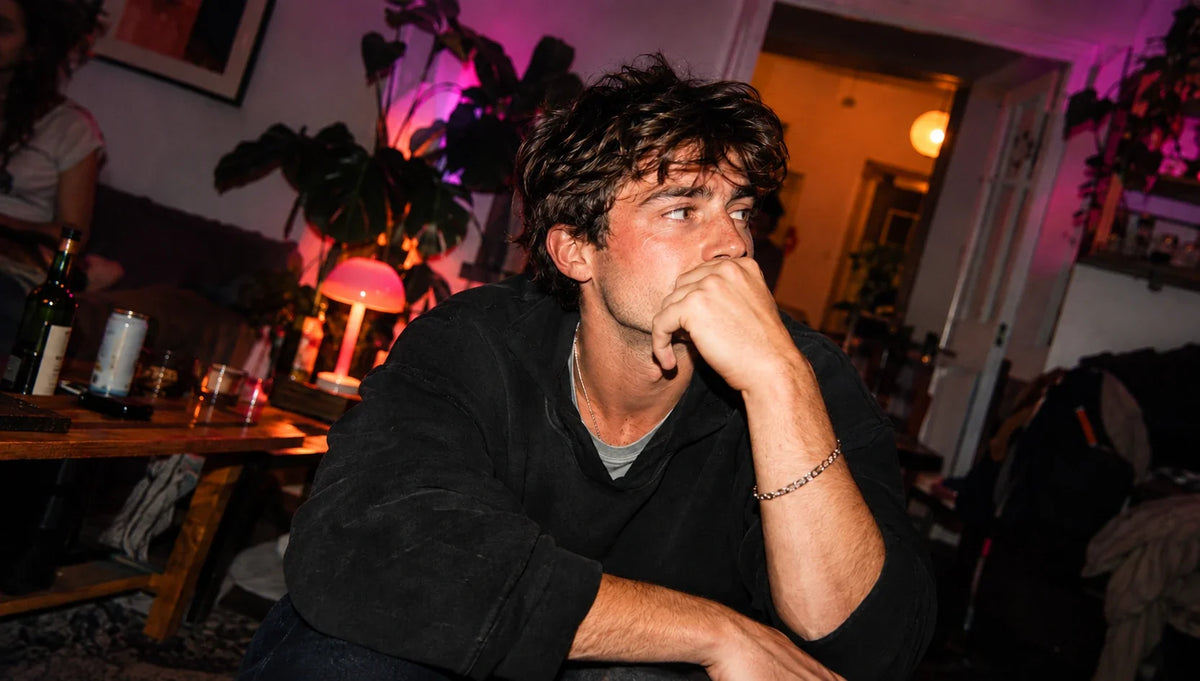 Young man sitting at a party looking thoughtful while quitting vaping cold turkey
